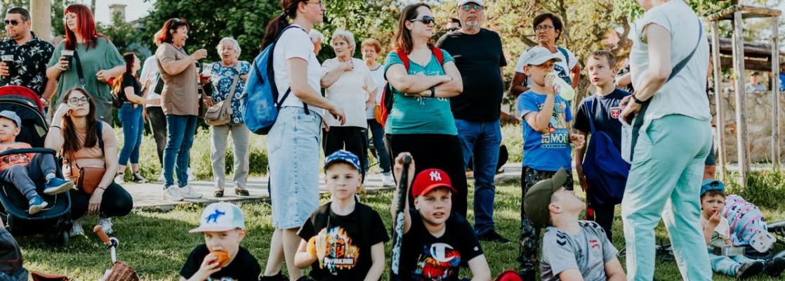 A diverse group of families and children enjoying an outdoor event on a sunny day in a park setting.